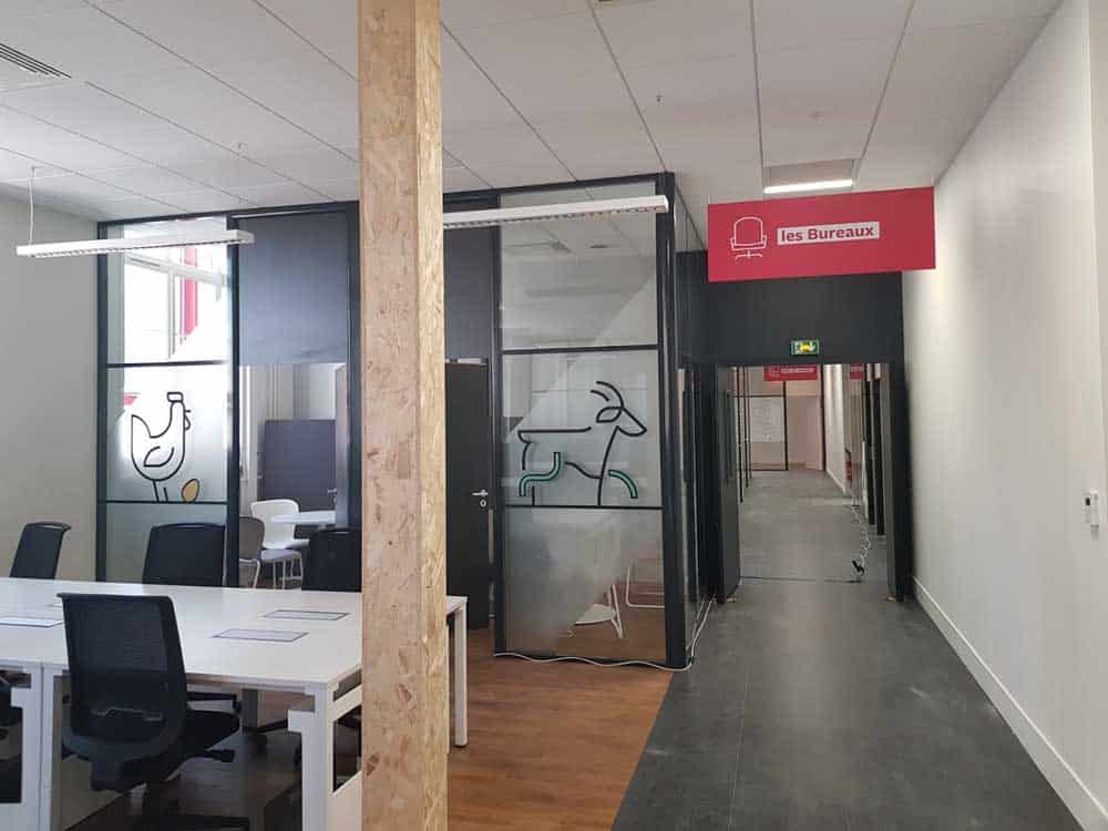 Les Bureaux : Aménagement d'Espace de Travail Moderne Espace de travail moderne avec cloisons vitrées, décorations animales et panneau signalétique rouge les Bureaux.